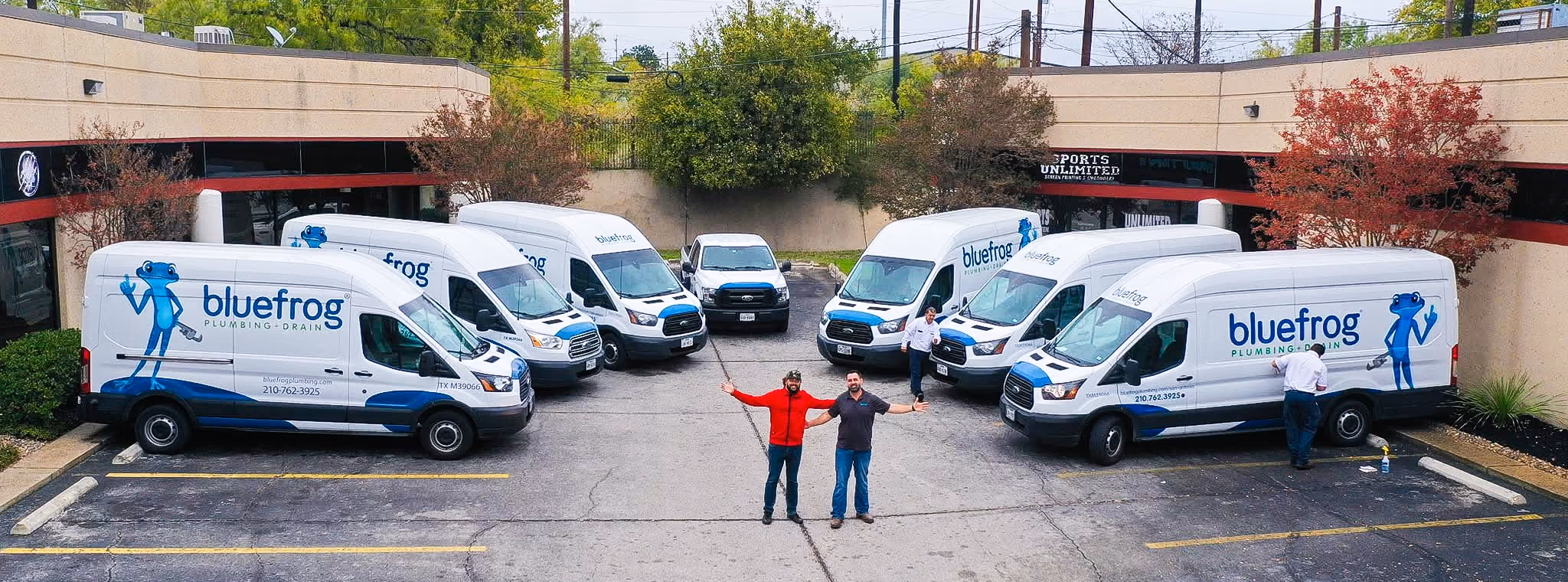 A home-service client's fleet of branded vans lined up outside their premises, with two of the owners standing between them.
